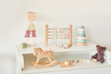 wooden toys in the children's room, chest of drawers and a white bed, the interior of the children's bedroom