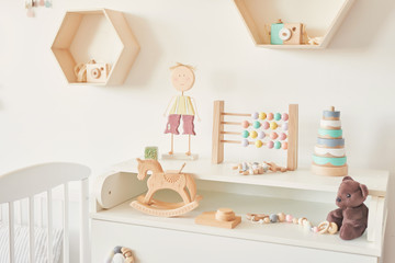 wooden toys in the children's room, chest of drawers and a white bed, the interior of the children's bedroom