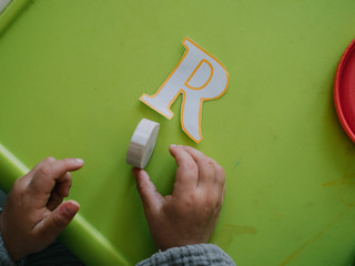Three year old girl painting with colors on green table