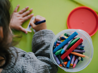 Three year old girl painting with colors on green table