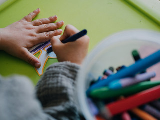 Three year old girl painting with colors on green table
