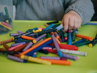 Three year old girl painting with colors on green table