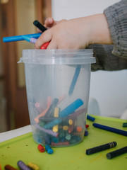 Three year old girl painting with colors on green table