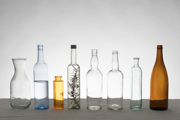 Verschiedene Glasflaschen vor weißem Hintergrund auf Tischdecke aus Leinen, im Gegenlicht