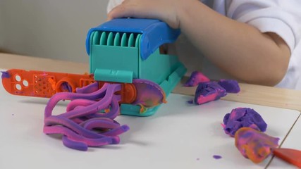 A two years old preschool child playing with modeling clay (compound). Smiling and looking at the camera. Early childhood education to children concept