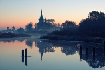 Fototapeta na wymiar Old churches at fog sunrise in Dunilovo, Russia