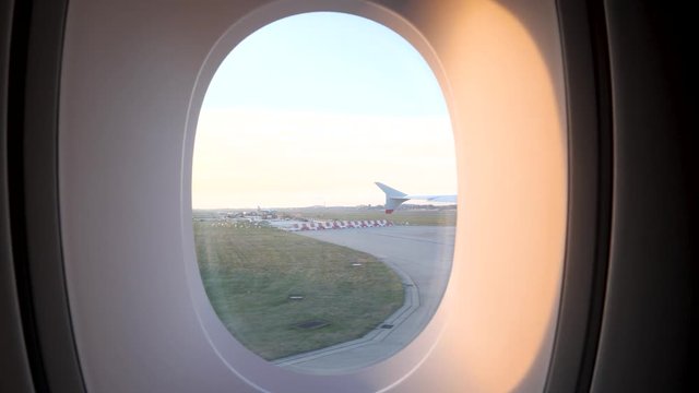 Airplane taxiing on the runway at Airport, Viewpoint from a passenger window, going past with plane in the background and the sun shining in, 4k