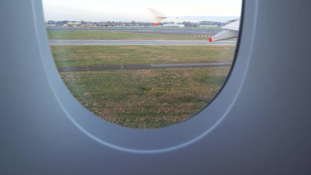 Close up of a slipstream on the grass as we taxi on the runway, view from an airplane window