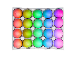 Fresh rainbow color eggs in a tray isolated on white background. Colorful eggs in egg tray for easter, top view