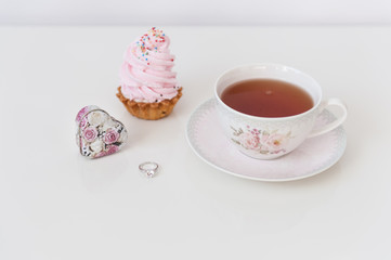 Morning tea with merengue and ring on white table. Marriage proposal -  surprise. Minimalism, copy space,  close up, soft focus.