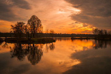 Beautiful landscape of the Rhine River between France and Germany in winter at dusk with sunset colors and dramatic sky. Plobsheim, near Strasbourg, Alsace, France.