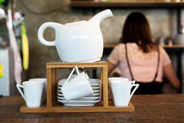 Set of Modern teapot with tea cups in coffee shop background