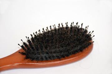 Brown comb with hair loss problem on light background. Healthcare concept. Selective focus. Closeup of comb brush with loss hair with copy space. Сomb with hair fall