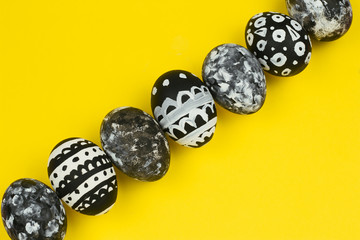 top view collection of dyed black and white easter eggs on a yellow background