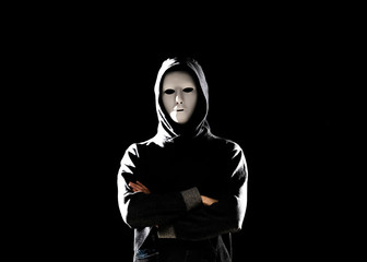 Computer hacker in white mask and hoodie. Obscured dark face. Data thief, internet fraud, darknet and cyber security concept.