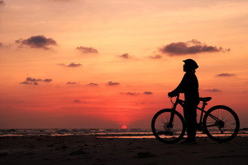 Naklejka na ściany i meble Silhouette of woman and bicycle at sunset background