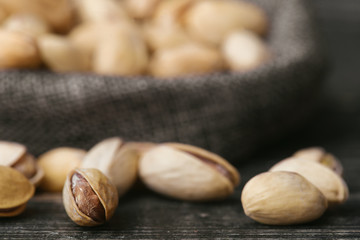 Roasted pistachios  in gray bag on textured  dark wooden background, top view. Copy space. 