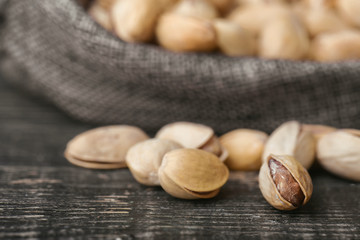 Roasted pistachios  in gray bag on textured  dark wooden background, top view. Copy space. 