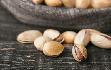 Roasted pistachios  in gray bag on textured  dark wooden background, top view. Copy space. 