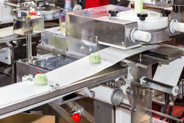 close up chinese or asian food steamed stuffed buns on automatic belt conveyor of food making machine in production line for high technology industrial manufacturing