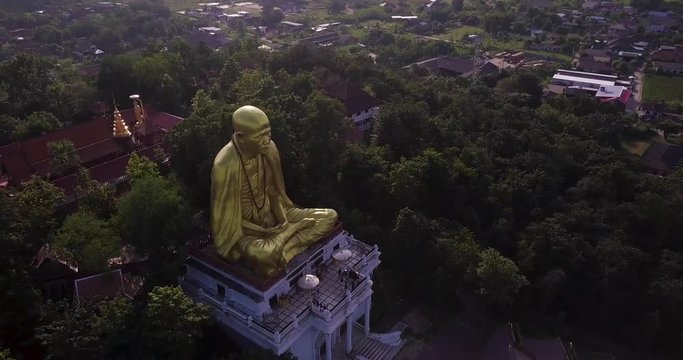 Drone fly over a big golden buddha statue in Lamphun, Thailand. TILT DOWN