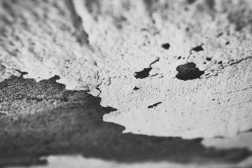 Top view of white paint peeling off gray wall.