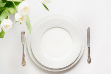 Fototapeta na wymiar Easter dinner. Table setting with white tulip on white table.