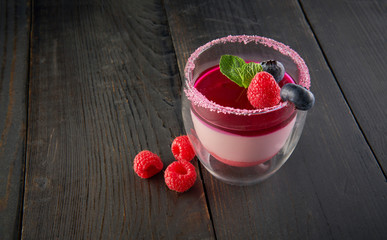 Panna cotta dessert with fresh blueberries and raspberry on dark rustic wooden background