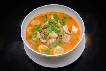 Tom Yum Goong spicy soup traditional food cuisine in Thailand , Top view on black background