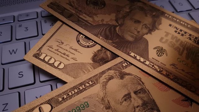 Replica US Dollar falling onto gold bitcoin on a keyboard in decreasing nominations