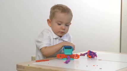 A two years old preschool child playing with modeling clay (compound). Smiling and looking at the camera. Early childhood education to children concept