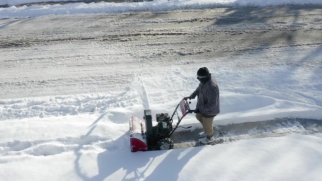 Aerial view shows man Snow Blowing sidewalk.