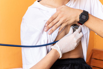 Doctor examining heartbeat of boys with stethoscope.