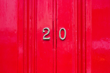 House number twenty with 20 in bronze numbers on a red wooden door