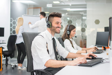 Fototapeta na wymiar Cheerful customer service agents working in call center