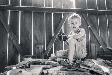 Little boy working in a shed with wood