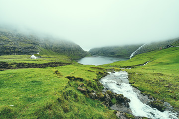 Beautiful peaceful church in Saksun valley next to the waterfall in foggy weather, Faroe Islands, North Europe, hidden gem for travel destination