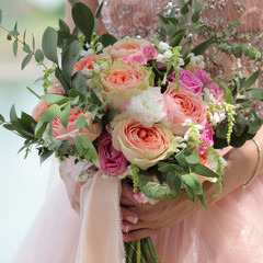 Beautiful bridal bouquet in hands of the bride. Wedding bouquet of peach roses by David Austin,  single-head pink rose aqua, eucalyptus, ruscus, gypsophila