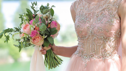 Beautiful bridal bouquet in hands of the bride. Wedding bouquet of peach roses by David Austin,  single-head pink rose aqua, eucalyptus, ruscus, gypsophila