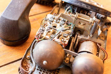 Inside old telephone receiver on wooden table background.