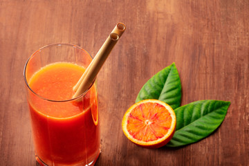 A closeup of reusable bamboo straws in a glass of vibrant orange juice, with a place for text. Selective focus. Zero waste concept