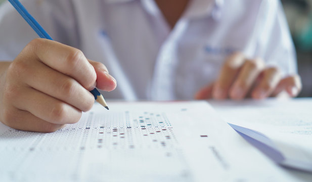 Answers to the questions.Students hand holding pencil writing selected choice on answer sheets and.students testing doing examination.Exam carbon paper computer sheet.