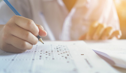 Answers to the questions.Students hand holding pencil writing selected choice on answer sheets and.students testing doing examination.Exam carbon paper computer sheet.