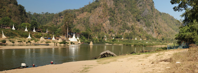 wide panoramic view of a river on the border between Thailand and Myanmar with white stupas and pagodas along the hillside, Northern Thailand, Southeast Asia