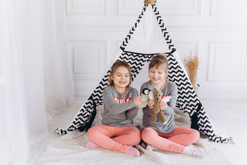 Two positive cheerful girls playing together at home with toys in children wigwam. Friendship, childhood, happiness concept © Andreshkova Nastya