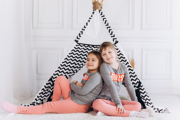 Two positive cheerful girls playing together at home with toys in children wigwam. Friendship, childhood, happiness concept © Andreshkova Nastya