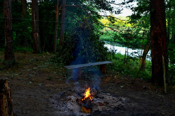 Hut from the branches of the tree for the night in the forest during a journey through the wild nature in the Republic of Belarus on the river Bobr. Bonfire for cooking and heat © MaxSafaniuk