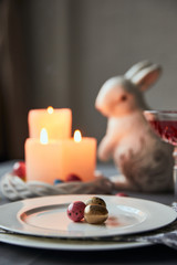 selective focus of plates with colorful eggs, wine in crystal glass, candles and decorative bunnie on table at home