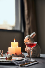 selective focus of plates with eggs, wine in crystal glass and decorative rabbit  on table at home