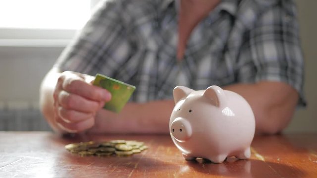 Woman putting credit card into piggy bank. The concept of saving money and investment.